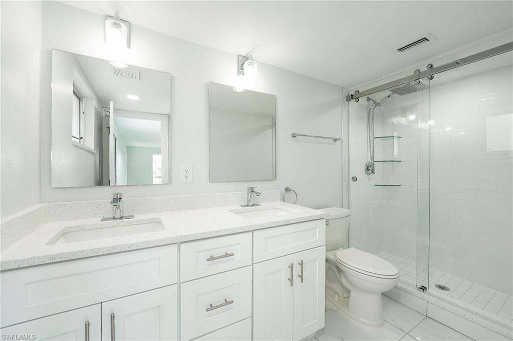 320 Bow Line Drive Naples, FL 34103 - Photo 14 of 20 a bathroom with a toilet a sink a mirror a shower a vanity and window
