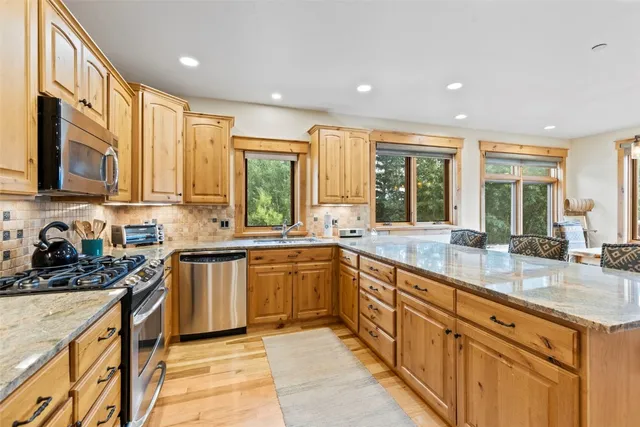 a large kitchen with stainless steel appliances granite countertop a sink and cabinets