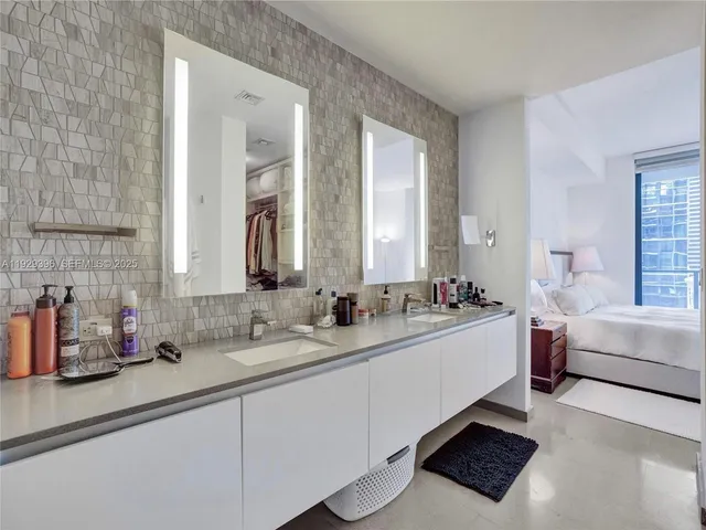 a bathroom with double vanity sinks a mirror and a bathtub
