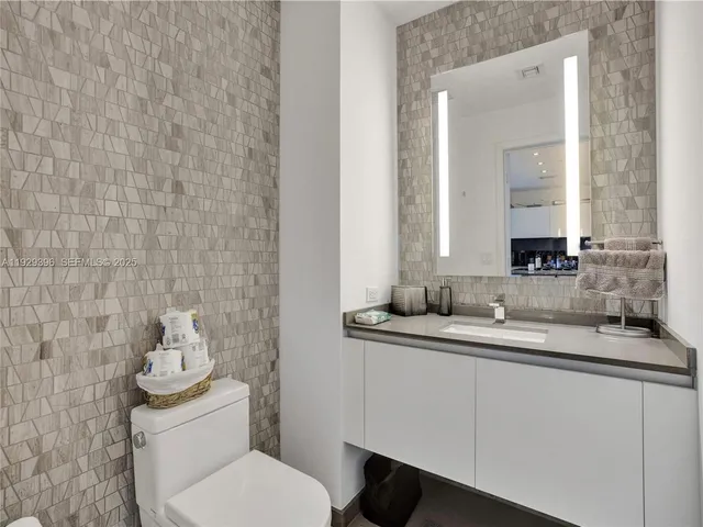 a bathroom with a granite countertop toilet sink and mirror