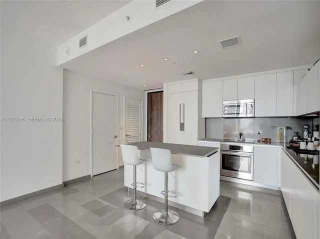 a kitchen with stainless steel appliances a stove a sink and white cabinets