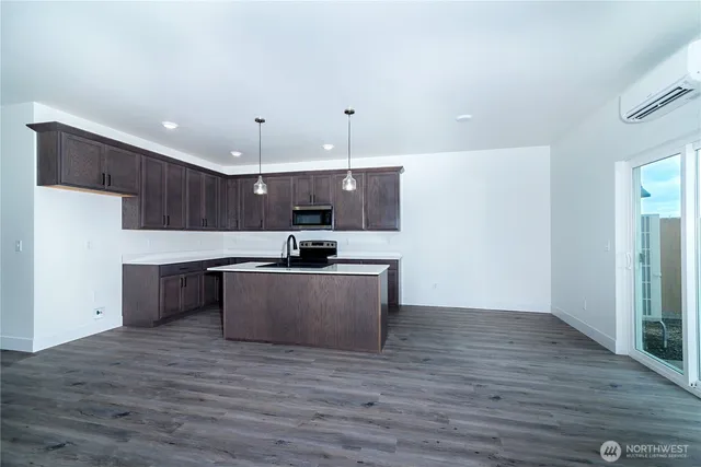 a view of kitchen with kitchen island stainless steel appliances a sink and wooden floor