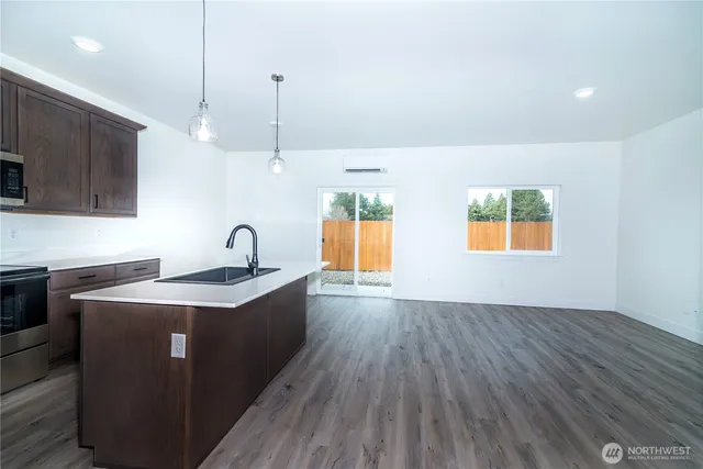 a kitchen with stainless steel appliances granite countertop a sink a stove a refrigerator cabinets and wooden floor