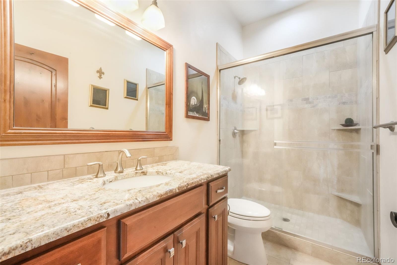 4330 Settlers Ranch Road Colorado Springs, CO 80908 - Photo 31 of 50 a bathroom with a granite countertop sink toilet and shower