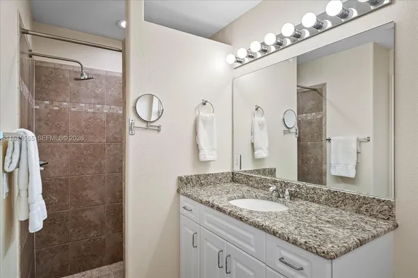 a bathroom with a granite countertop sink a mirror and a shower