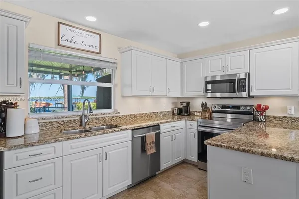 a kitchen with granite countertop white cabinets and stainless steel appliances