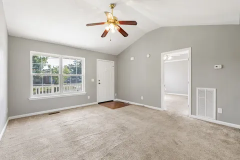 an empty room with ceiling fan and window