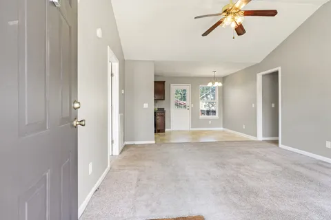 a view of an empty room and a chandelier fan