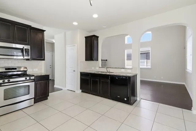a kitchen with stainless steel appliances granite countertop a stove a sink and a microwave