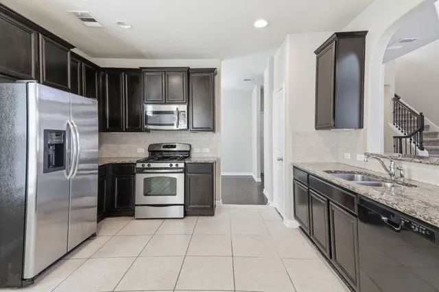 a kitchen with stainless steel appliances granite countertop a stove a refrigerator and a sink