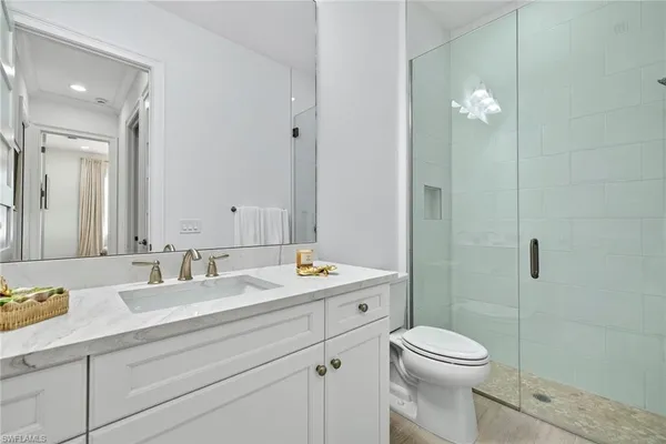 a bathroom with a toilet a sink a mirror a shower a vanity and window