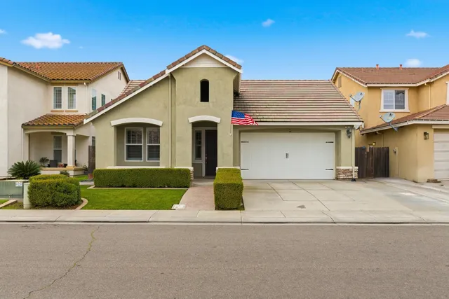 a front view of a house with garage and plants