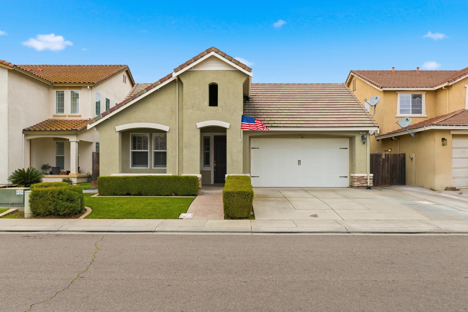 a front view of a house with garage and plants