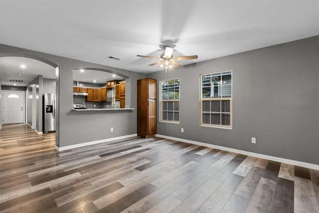 a view of an empty room with a window and a kitchen