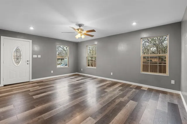 an empty room with windows and ceiling fan