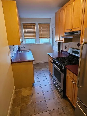 a kitchen with a sink a stove cabinets and a window