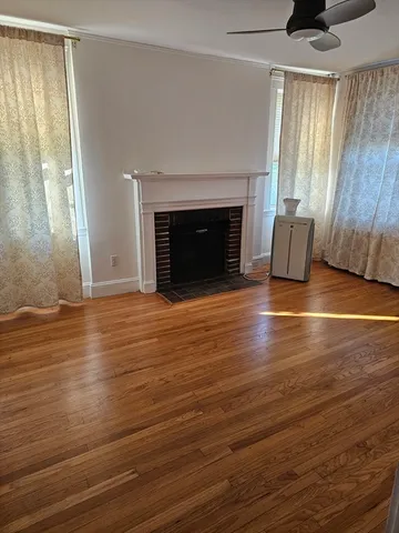 an empty room with wooden floor fireplace and windows