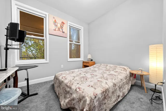 a bedroom with a bed a mirror on desk and a window