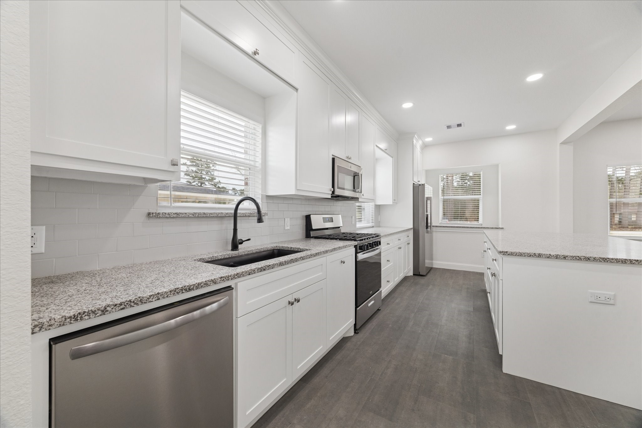 30731 Martens Road Tomball, TX 77375 - Photo 11 of 25 a kitchen with granite countertop a sink stainless steel appliances white cabinets and a window