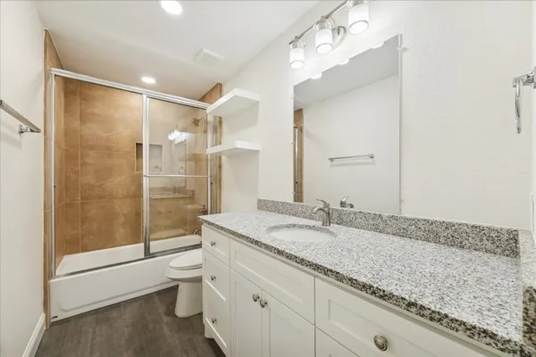a bathroom with a granite countertop sink a toilet and a shower