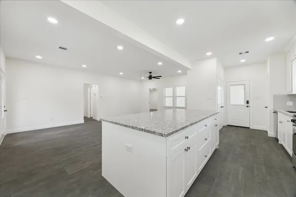 a kitchen with granite countertop a sink stainless steel appliances white cabinets and a window