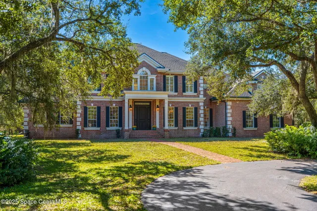 a view of a white house with a large pool and large trees
