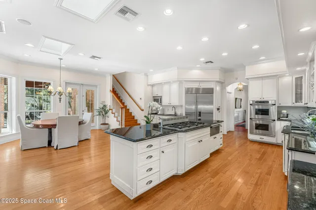 a large white kitchen with lots of counter space a sink and stainless steel appliances