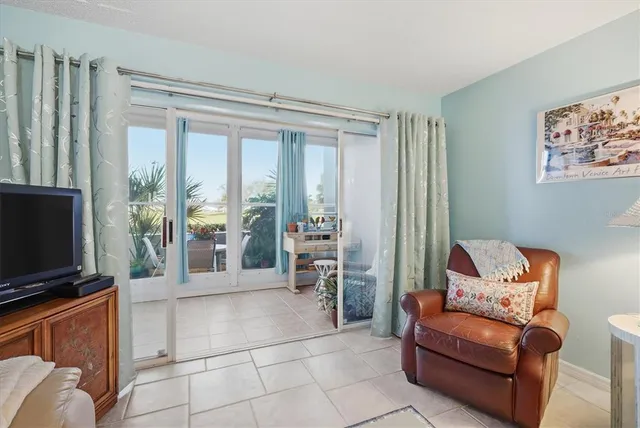 a living room with furniture a flat screen tv and a floor to ceiling window