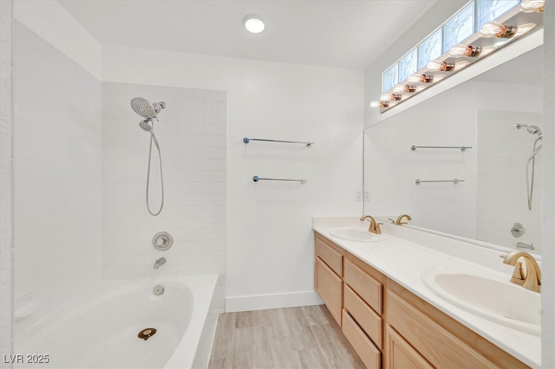 5421 Painted Mirage Road Las Vegas, NV 89149 - Photo 18 of 35 Bathroom featuring double vanity, tub / shower combination, a sink, and wood finished floors