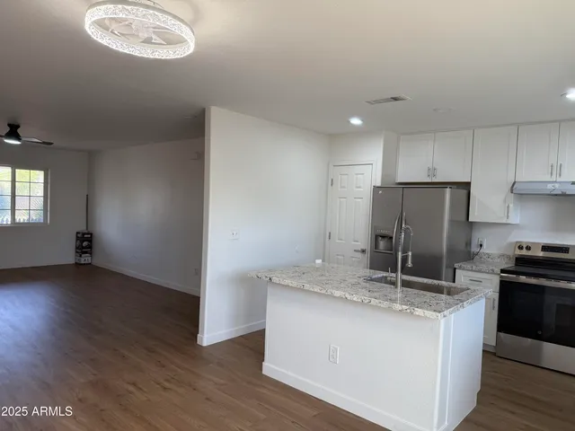 a kitchen with kitchen island granite countertop stainless steel appliances a sink stove refrigerator and cabinets