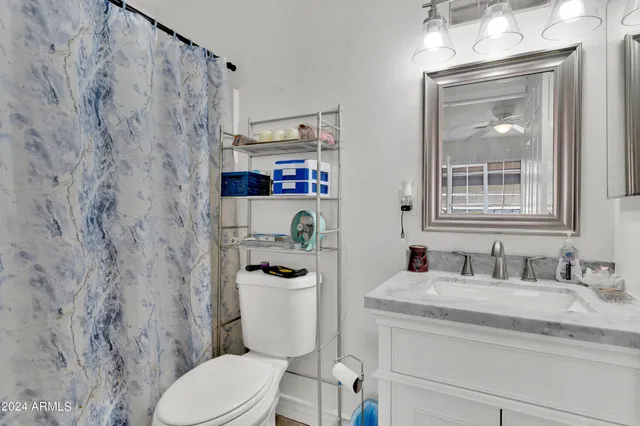 a bathroom with a granite countertop toilet sink and mirror