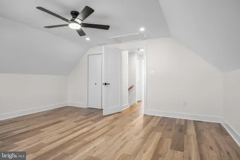 an empty room with wooden floor and a ceiling fan