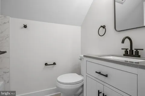 a bathroom with a granite countertop sink vanity mirror and toilet