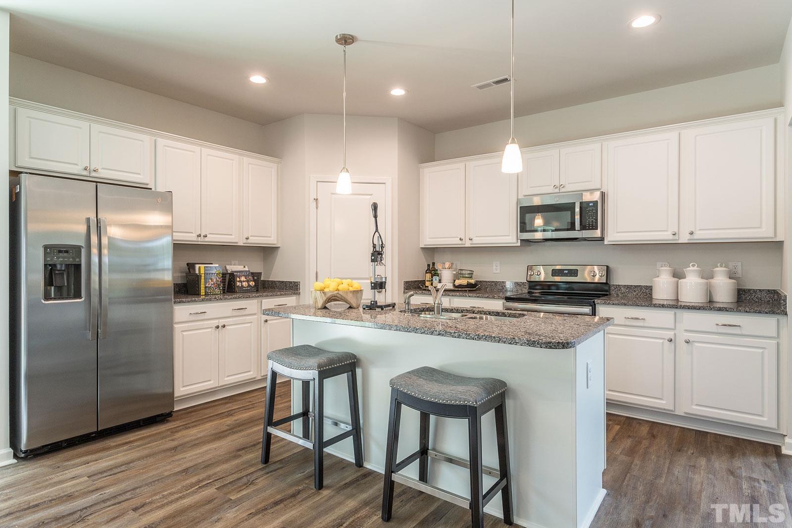a kitchen with kitchen island granite countertop a sink a counter top space stainless steel appliances and cabinets
