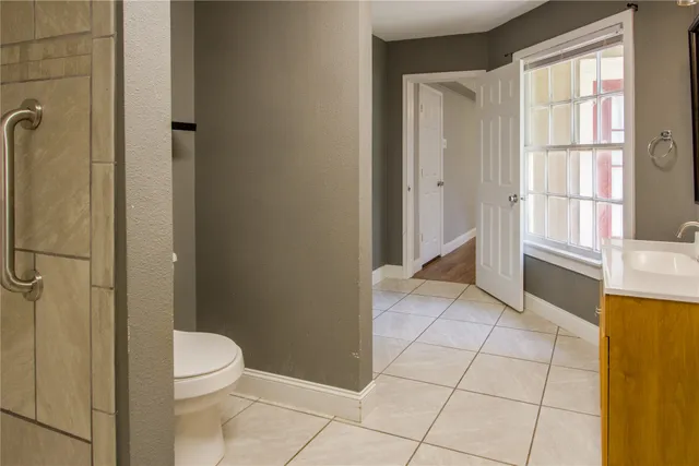 a bathroom with a granite countertop sink a toilet a window and shower
