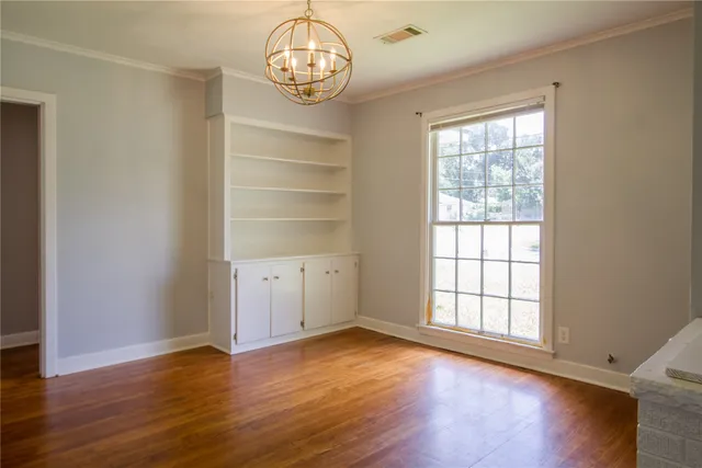 an empty room with wooden floor and window