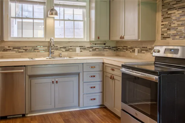 a kitchen with granite countertop a sink cabinets stainless steel appliances and a window