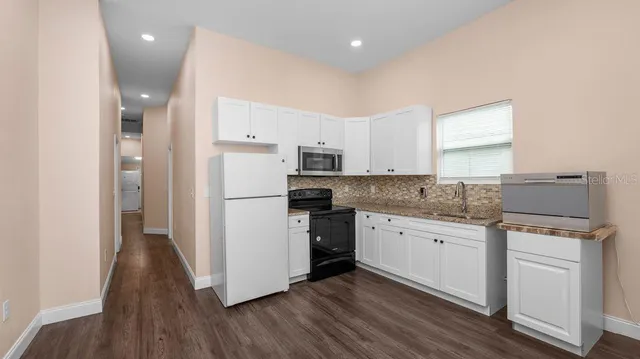 a kitchen with granite countertop a refrigerator stove top oven and sink
