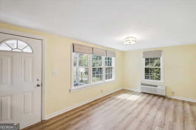 a view of an empty room with a window and wooden floor