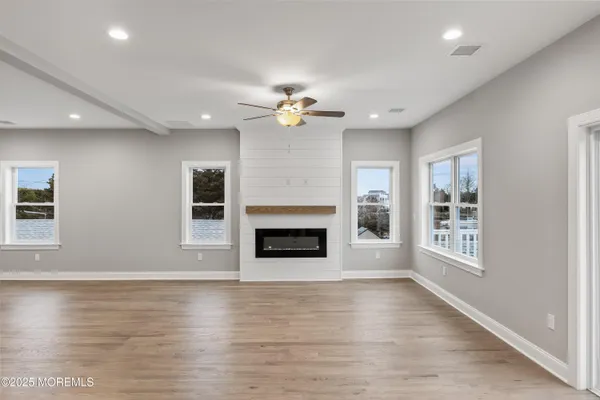 an empty room with windows fireplace and a kitchen