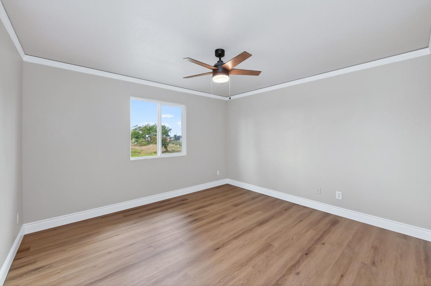 16564 Monreal Road Madera, CA 93636 - Photo 45 of 59 an empty room with wooden floor ceiling fan and windows