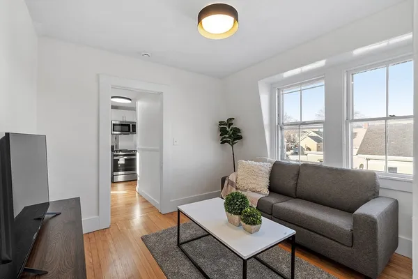 a living room with furniture wooden floor and a large window