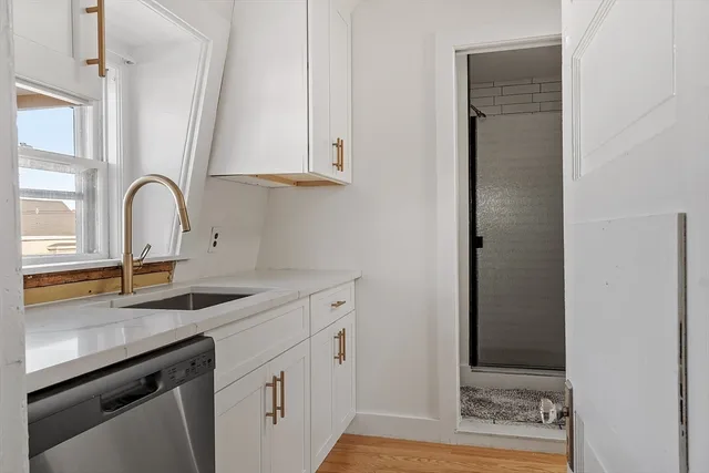 a kitchen with stainless steel appliances granite countertop a sink and dishwasher with white cabinets