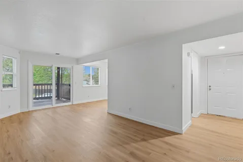 a view of an empty room with a window and wooden floor