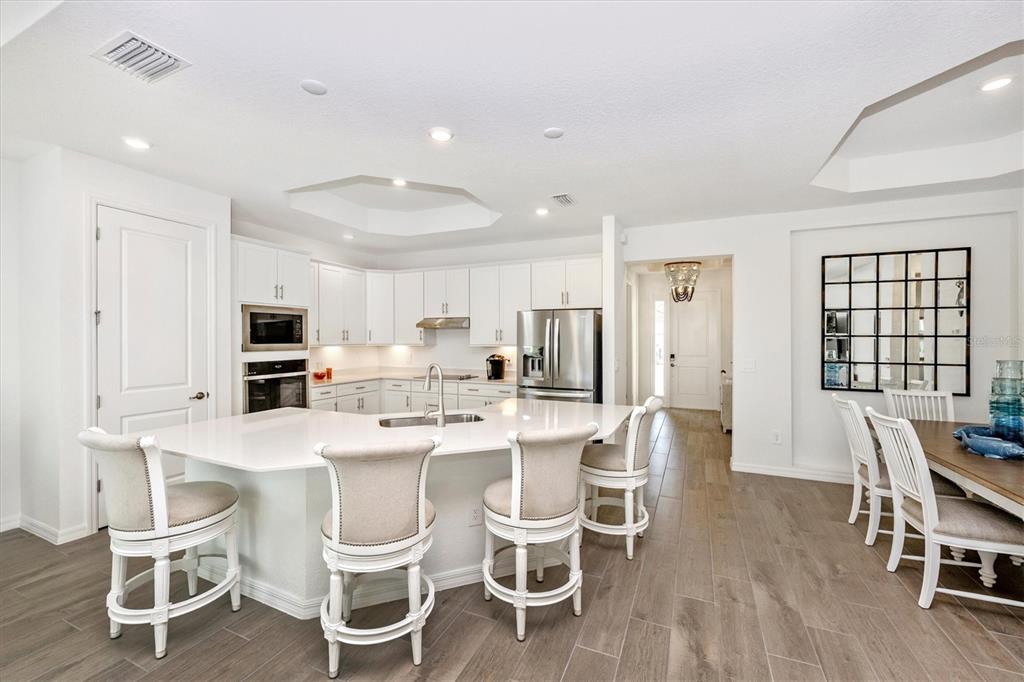 12950 Tulum Loop Venice, FL 34293 - Photo 11 of 98 a dining room with stainless steel appliances kitchen island granite countertop a dining table chairs and a refrigerator