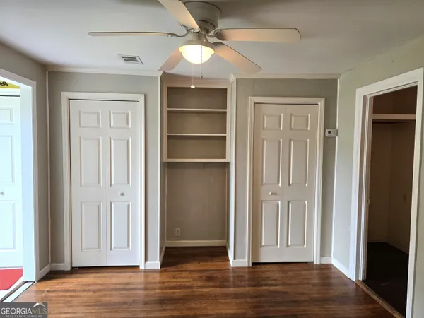 an empty room with wooden floor closet and windows