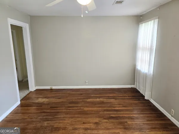 a view of an empty room with wooden floor and a window