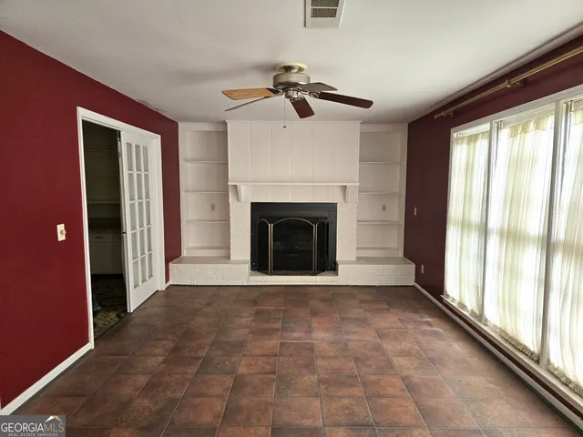 a view of an empty room with window and fire place