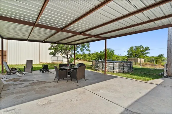 a view of a patio with table and chairs potted plants with floor to ceiling window