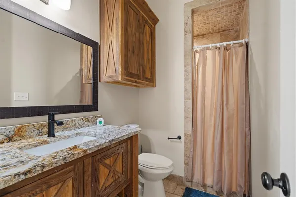 a bathroom with a granite countertop sink toilet and mirror